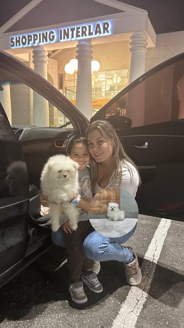 Mãe e filho abraçados com um filhote de Lulu da Pomerânia branco