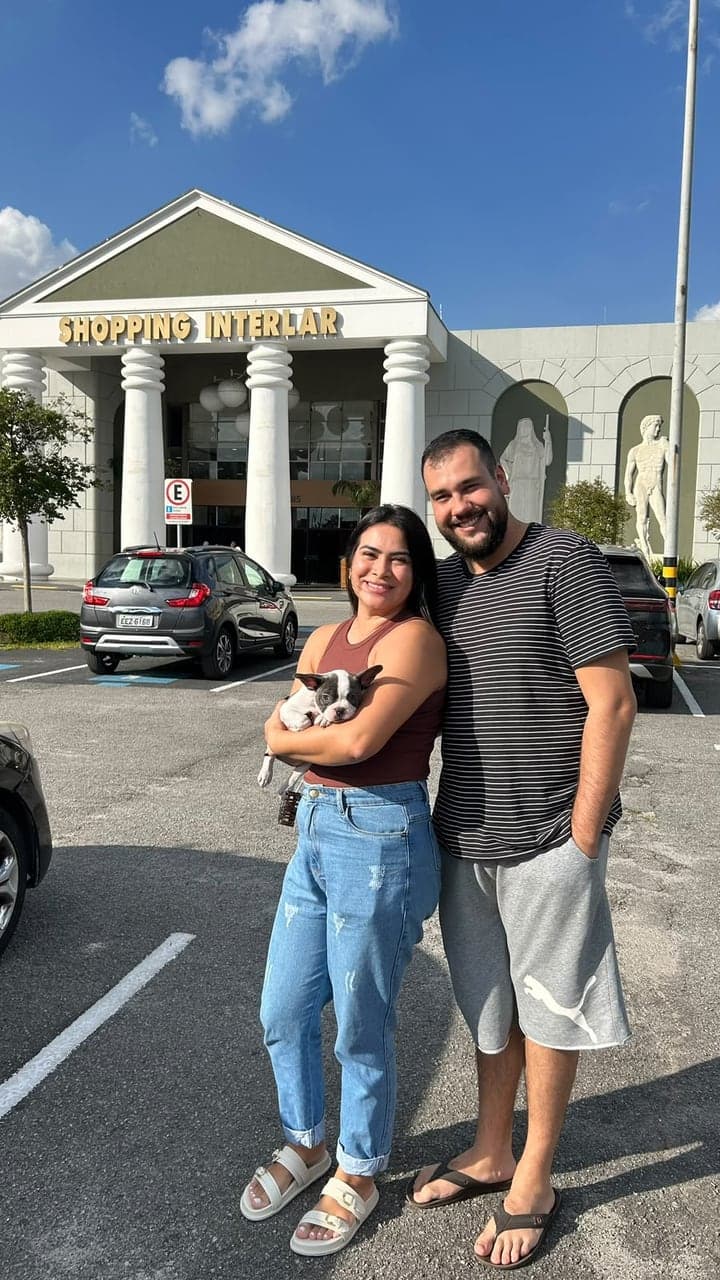 Casal sorridente com um filhote de Bulldog Francês preto e branco no colo
