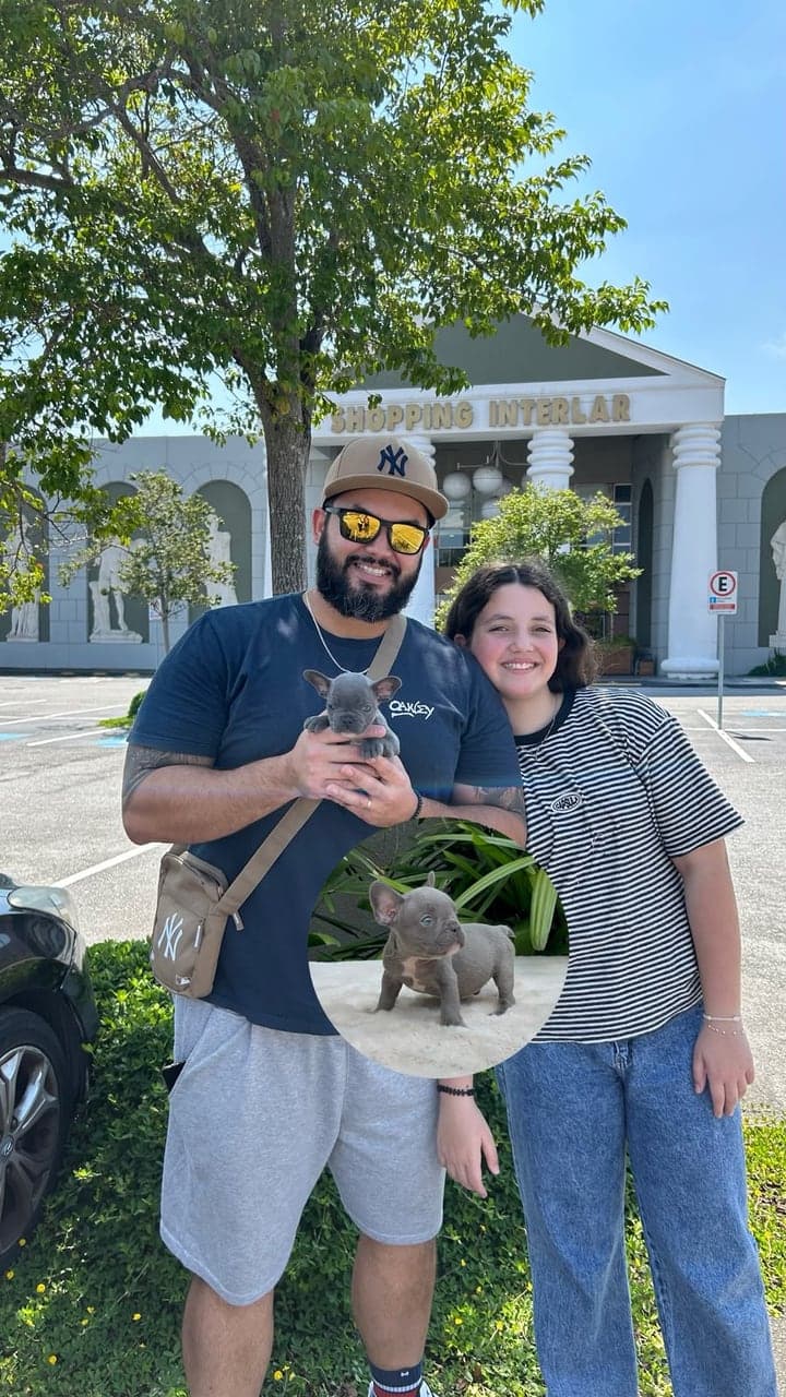 Pai e filha sorrindo com um filhote de Bulldog Francês azul