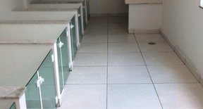 Espaço interno com piso claro e baias com divisórias de vidro