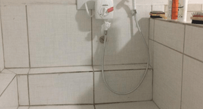 Área de banho revestida de azulejos, com chuveiro